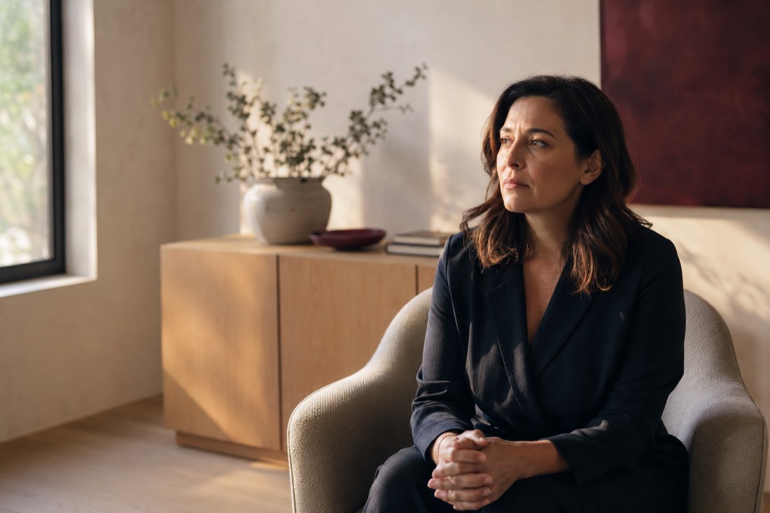 A composed adult woman sitting quietly in a refined office