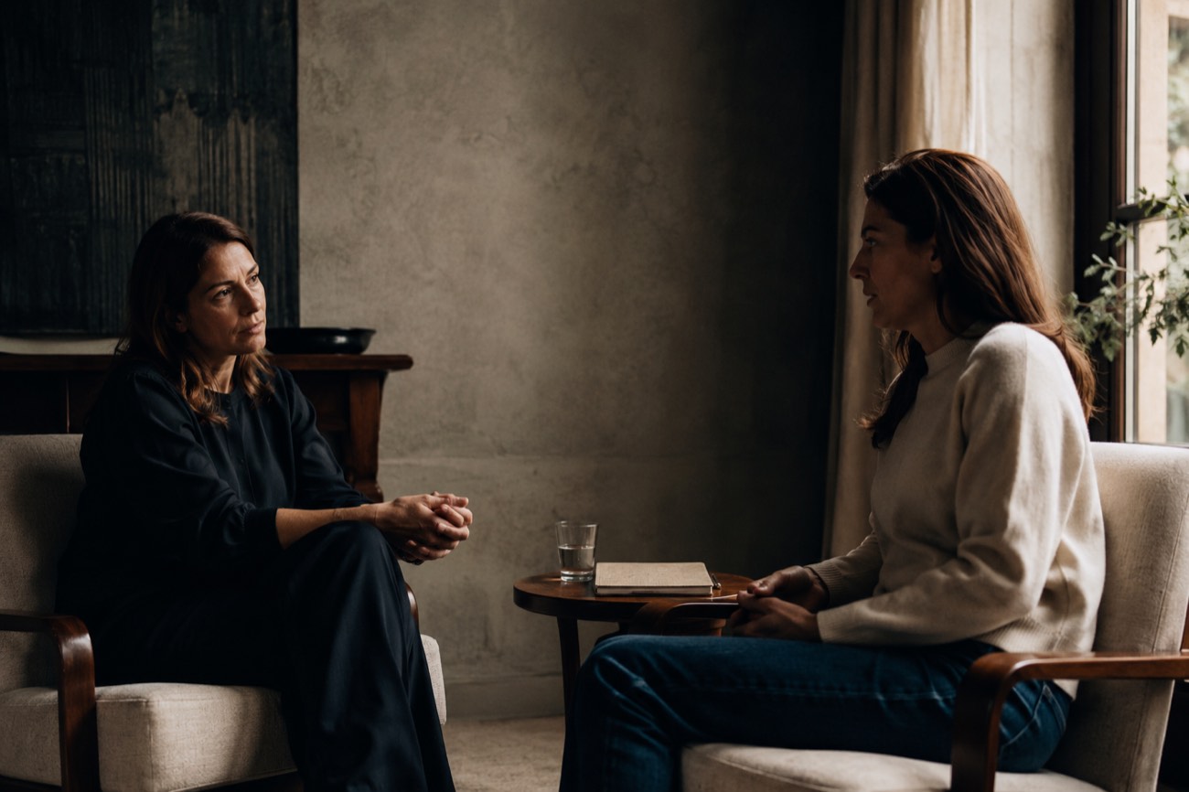 Two women in a focused, private one-on-one conversation in a quiet room
